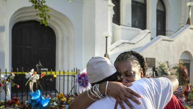 Mourners Cynthia Wright-Murphy, right, hugs her sister Carolyn Wright-Porcher, right, outside the Emanuel AME Church, Saturday, June 20, 2015  in Charleston, S.C. A steady stream of people brought flowers and notes and shared somber thoughts at a growing memorial in front of the church. (AP Photo/Stephen B. Morton)